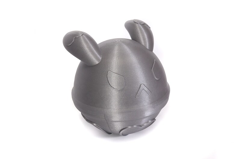 Op de afbeelding: Een grijs 3D-geprint speelgoed in de vorm van een konijn met grote oren. Het speelgoed heeft een rond lichaam en een platte bodem.