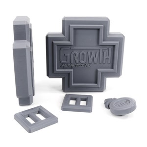 May include: A gray plastic toy set with a cross-shaped piece that says "GROWTH" and several smaller pieces.