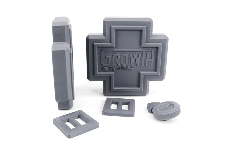 May include: A gray plastic toy set with a cross-shaped piece that says "GROWTH" and several smaller pieces.