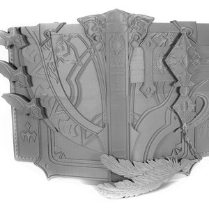 May include: A gray, intricately designed book with a feather bookmark. The book has a detailed, ornate cover with a decorative clasp and a small bell hanging from it.