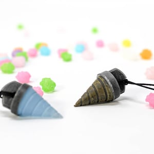 May include: Two small, detailed drill bit charms with black cords. One charm is blue and the other is brown and silver.