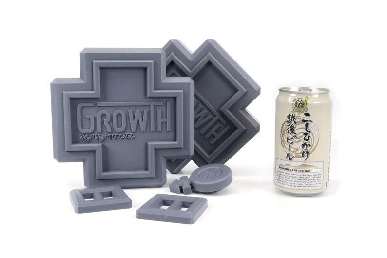 May include: A set of gray plastic building blocks with the word "GROWTH" printed on one of the blocks. The blocks are shaped like crosses and squares. A can of beer is also in the image.