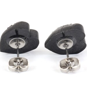 May include: A pair of black heart-shaped stud earrings with silver posts and butterfly backs.