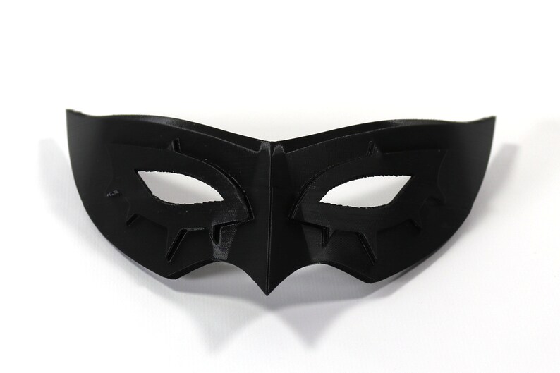 May include: A black masquerade mask with a stylized eye design. The mask is made of a smooth, hard material.