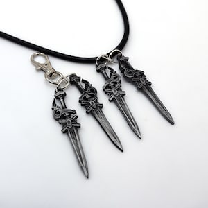 May include: A set of four silver-colored sword pendants with intricate designs, attached to a black cord and a silver clasp. The pendants are detailed with ornate handles and blades, ideal for fantasy enthusiasts.
