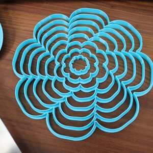 May include: A set of nine blue plastic flower-shaped cookie cutters of varying sizes.