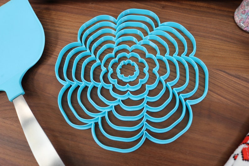 May include: A set of nine blue plastic flower-shaped cookie cutters of varying sizes.