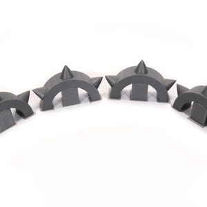 May include: Four grey plastic spiked arches, each with three spikes on top. The arches are arranged in a semi-circle.