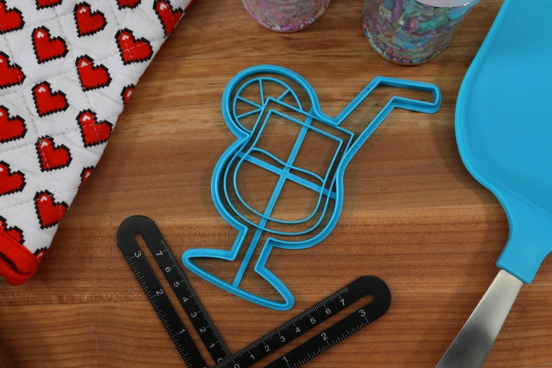 May include: Blue plastic cookie cutter shaped like a cocktail glass with a lime wedge and a straw.