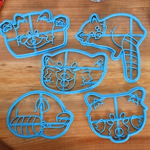 Może przedstawiać: Pięć niebieskich plastikowych foremek do ciasteczek w kształcie czerwonych pand. Formy znajdują się na drewnianej powierzchni.