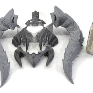 May include: A set of five gray, 3D printed dragon horns. The horns are in various sizes and shapes, and are arranged in a symmetrical pattern. A can of beer is included for scale.