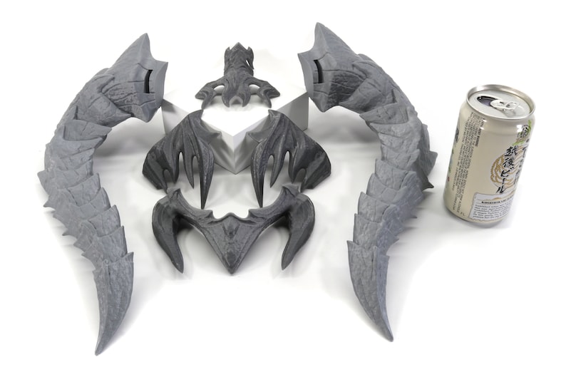 May include: A set of five gray, 3D printed dragon horns. The horns are in various sizes and shapes, and are arranged in a symmetrical pattern. A can of beer is included for scale.