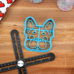 Puede incluir: Cortador de galletas de pl&aacute;stico azul con forma de cara de perro. El cortador tiene un dise&ntilde;o detallado con nariz, ojos y orejas.