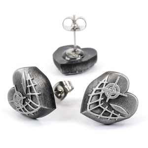May include: A pair of silver heart-shaped earrings with a geometric design. The earrings have a textured surface and a silver post.