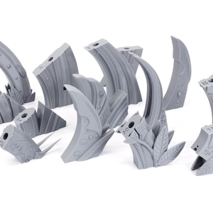 May include: A collection of gray, stylized, decorative rock formations with floral and geometric details. The pieces vary in shape and size, with some featuring curved designs and others with holes.