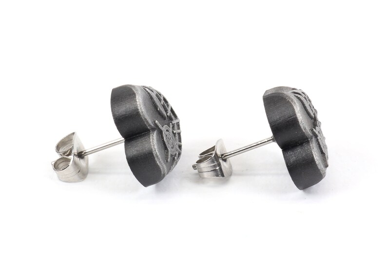May include: A pair of black heart-shaped stud earrings with a detailed design. The earrings have silver posts and backs.