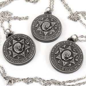 May include: Three silver-colored pendant necklaces. Each pendant is a circular, dark gray medallion with engraved text and a central star design. The necklaces have delicate silver chains and clasps.