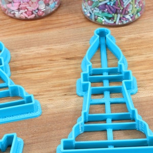 May include: Three blue plastic cookie cutters shaped like chess pieces. The pieces are a pawn, a bishop, and a rook.