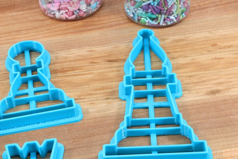 May include: Three blue plastic cookie cutters shaped like chess pieces. The pieces are a pawn, a bishop, and a rook.
