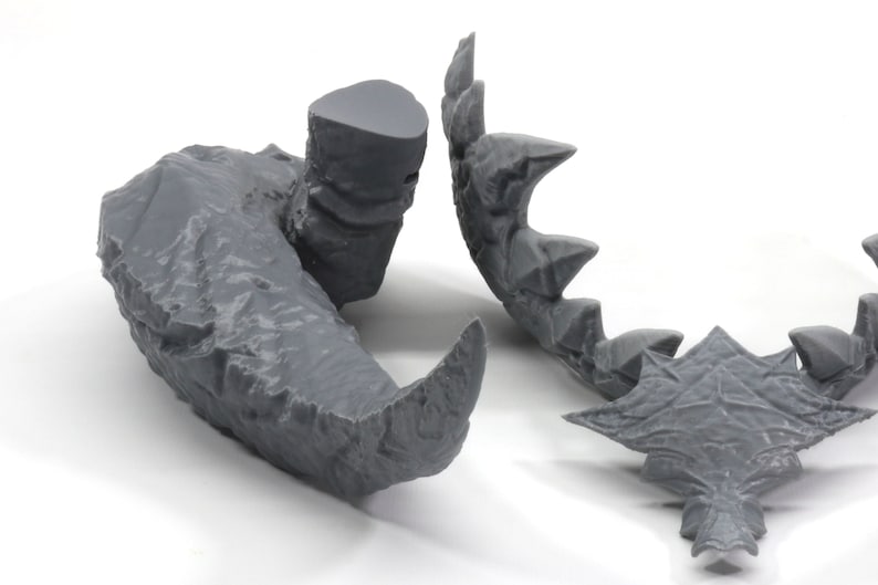 May include: A 3D printed gray model of a dragon's head, with a separate jaw piece. The head is detailed with scales and teeth.