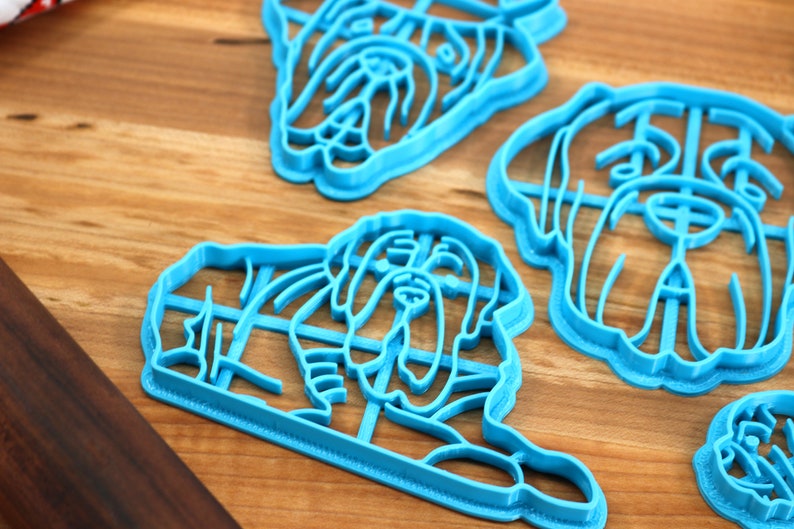 Peut inclure: Quatre emporte-pi&egrave;ces en plastique bleu en forme de t&ecirc;te de chien. Les emporte-pi&egrave;ces sont sur une surface en bois.