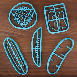 Pode incluir: Cinco cortadores de biscoitos de plástico azul em forma de picles, cachorro-quente, pão e dois estilos diferentes de pepinos.