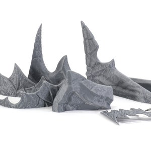May include: A set of grey plastic dragon wings for a miniature figure. The wings are detailed with textured scales and sharp points.
