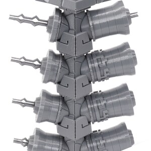 May include: A close-up of a gray 3D printed model of a tower with multiple cannons. The cannons are arranged in a vertical stack and have a detailed design.
