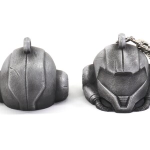 Puede incluir: Un llavero de metal plateado que presenta una r&eacute;plica detallada del casco de un personaje de videojuego. El llavero tiene un lazo de metal para sujetarlo a las llaves o a una bolsa.