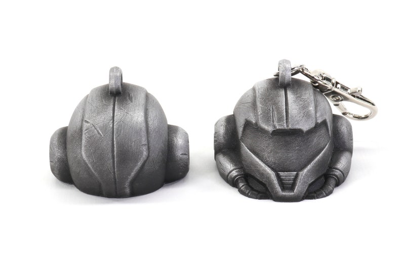 Puede incluir: Un llavero de metal plateado que presenta una r&eacute;plica detallada del casco de un personaje de videojuego. El llavero tiene un lazo de metal para sujetarlo a las llaves o a una bolsa.