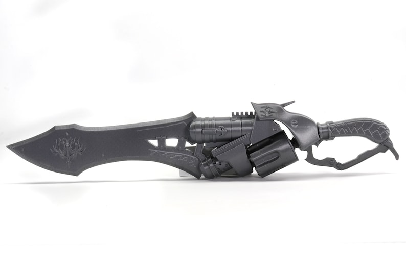 May include: A black, detailed, futuristic-style weapon with a blade and a pistol grip. The weapon has a textured handle and a decorative design on the blade.