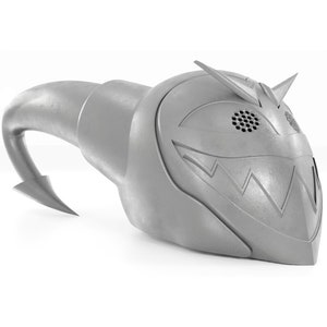 May include: A gray, 3D printed helmet with a sharp, pointed design. The helmet has a large, toothy grin and a small, round speaker on the side.