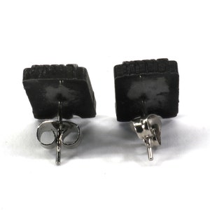 May include: A pair of black square stud earrings with silver posts and backs.