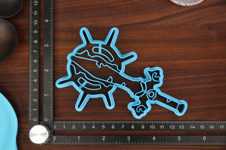 Puede incluir: Un cortador de galletas de pl&aacute;stico azul con forma de espada y rueda. El cortador mide aproximadamente 15 cm de largo y 10 cm de ancho.