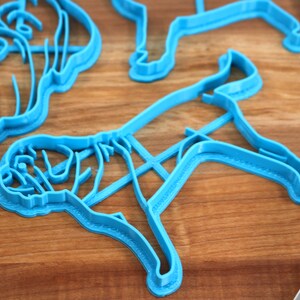 Peut inclure: Quatre emporte-pi&egrave;ces en plastique bleu en forme de chien. Les emporte-pi&egrave;ces sont sur une surface en bois.