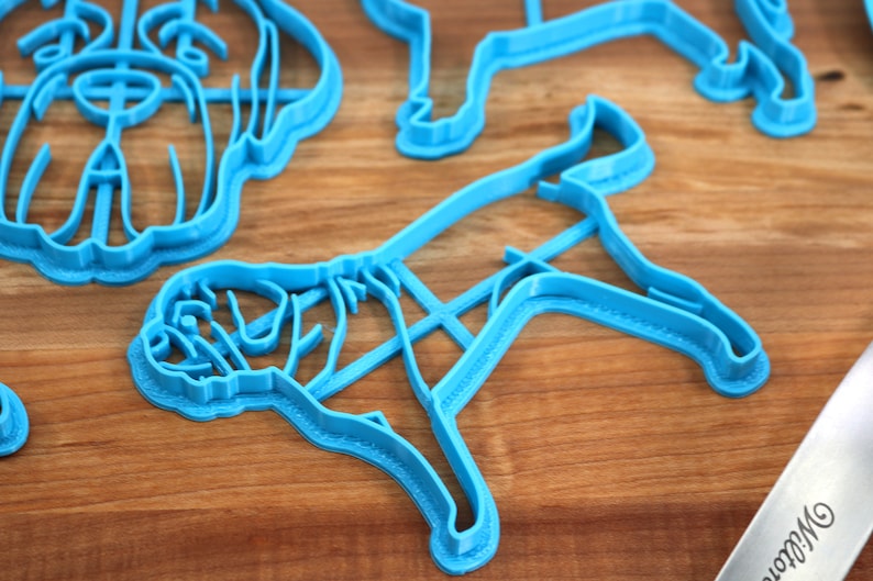 Peut inclure: Quatre emporte-pi&egrave;ces en plastique bleu en forme de chien. Les emporte-pi&egrave;ces sont sur une surface en bois.