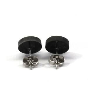 May include: A pair of black stud earrings with silver posts and butterfly backs.