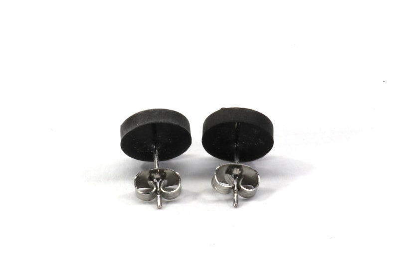 May include: A pair of black stud earrings with silver posts and butterfly backs.