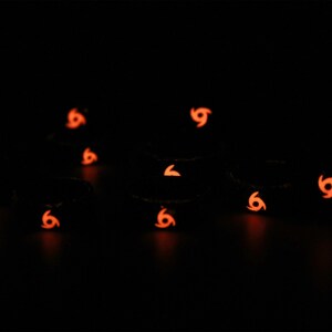 May include: A group of nine black silicone rings with a glow-in-the-dark orange swirl design.