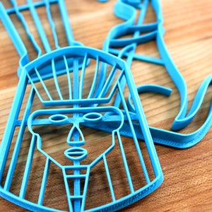 May include: A blue plastic cookie cutter shaped like a pharaoh's head with a headdress. The cutter is detailed with facial features and a patterned headdress.