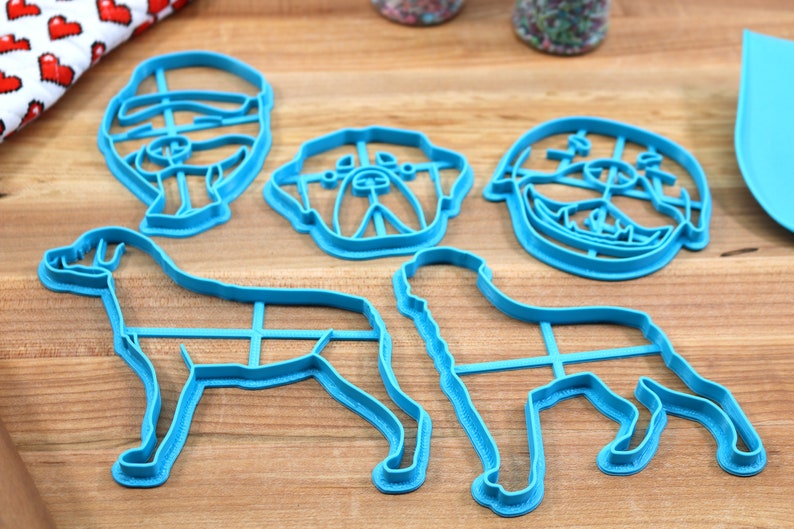 May include: Set of five blue plastic cookie cutters shaped like dogs. The cutters include a bulldog, a labrador, a pug, and two other dog breeds.