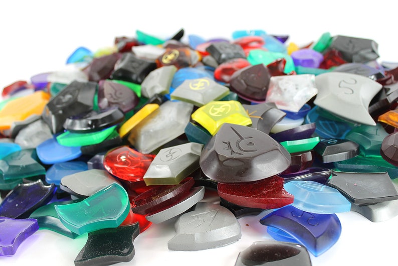 Puede incluir: Un mont&oacute;n de piezas de juego de pl&aacute;stico de colores, transl&uacute;cidas y opacas. Las piezas son de diversas formas y tama&ntilde;os, algunas con un s&iacute;mbolo o dise&ntilde;o.
