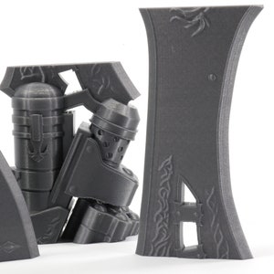 May include: A set of four gray 3D printed pieces with intricate designs. The pieces are made of a smooth, matte plastic and have a slightly textured surface. The pieces are designed to be assembled together to create a larger object.