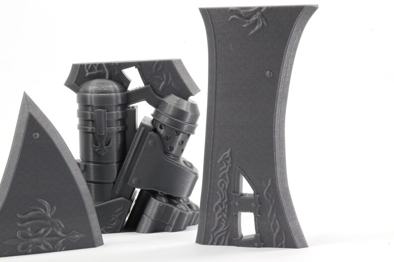May include: A set of four gray 3D printed pieces with intricate designs. The pieces are made of a smooth, matte plastic and have a slightly textured surface. The pieces are designed to be assembled together to create a larger object.