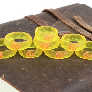 May include: Eight yellow plastic rings with a red design. The rings are stacked on top of each other.