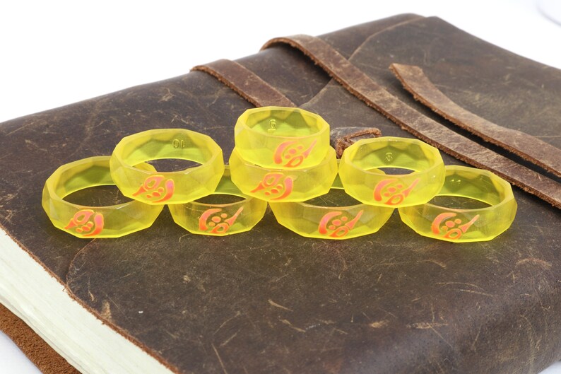 May include: Eight yellow plastic rings with a red design. The rings are stacked on top of each other.
