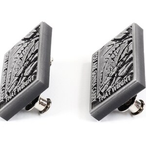 May include: Two silver-coloured pins with a cracked, textured surface. The text on the pins reads "YOU ARE GONNA CARRY THAT WEIGHT".