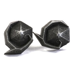 May include: A pair of silver-colored metal earrings with a geometric design. The earrings are shaped like a spiral with a star-shaped center.