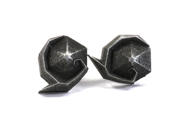 May include: A pair of silver-colored metal earrings with a geometric design. The earrings are shaped like a spiral with a star-shaped center.
