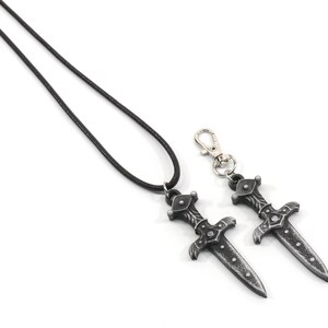 May include: A black leather cord necklace with a silver sword pendant. A matching silver sword keychain is also included.